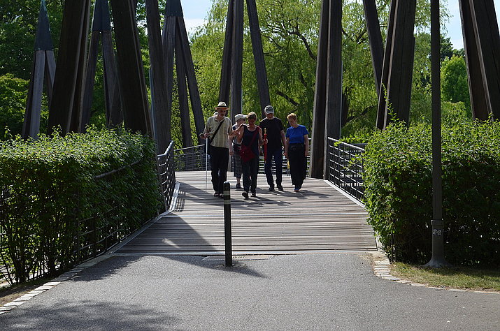 Personen laufen bei Sonnenschein über die Rhizomatische Brücke
