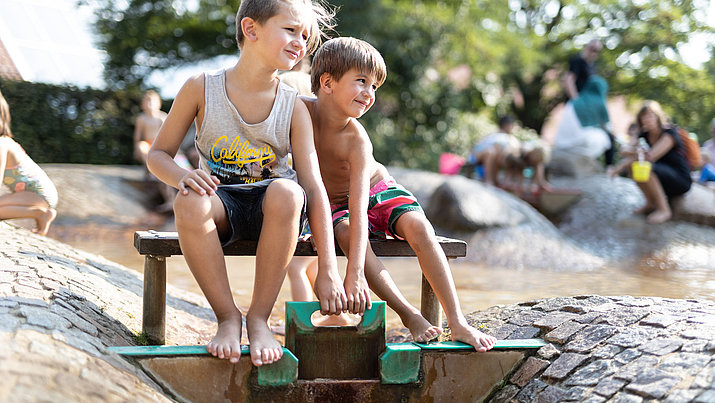 Zwei Kinder an der Schleuse am Wasserspielplatz